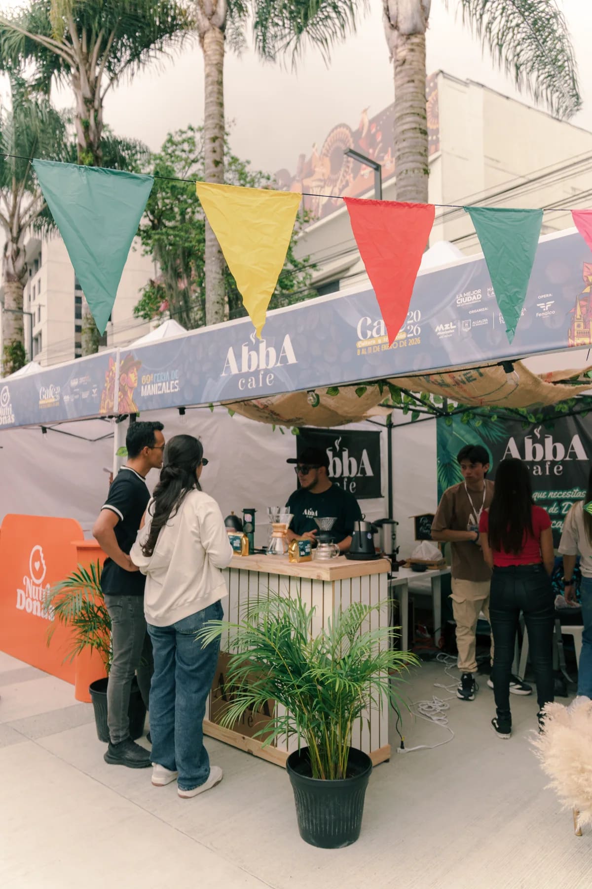 Stand de Abba Café con banderines de colores y visitantes alrededor