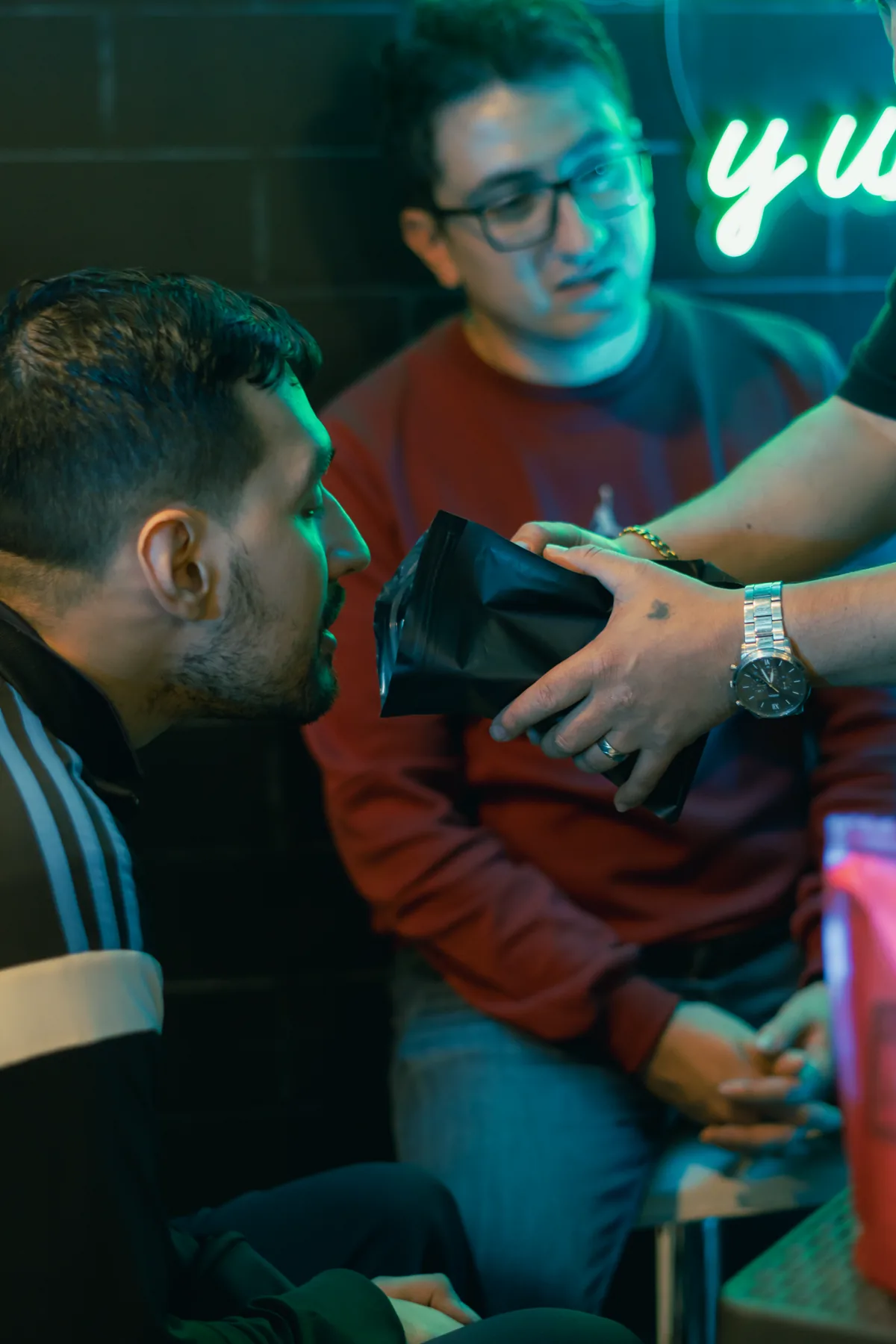 Tres amigos catando café en comunidad bajo el neón de Abba
